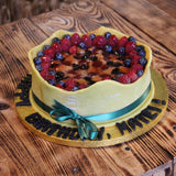 Vegan celebration cake topped with marzipan icing, filled with banana, raspberries and blueberries, decorated and handcrafted in North London