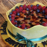 Vegan celebration cake topped with marzipan icing, filled with banana, raspberries and blueberries, decorated and handcrafted in North London