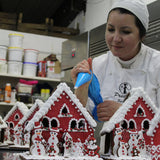 Baker decorating gingerbread houses in a kitchen setting
