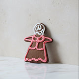 Gingerbread cookies shaped like a person with pink icing on a wooden surface
