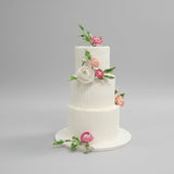 Three-tiered Medovik wedding cake with sugar floral decorations on a gray background