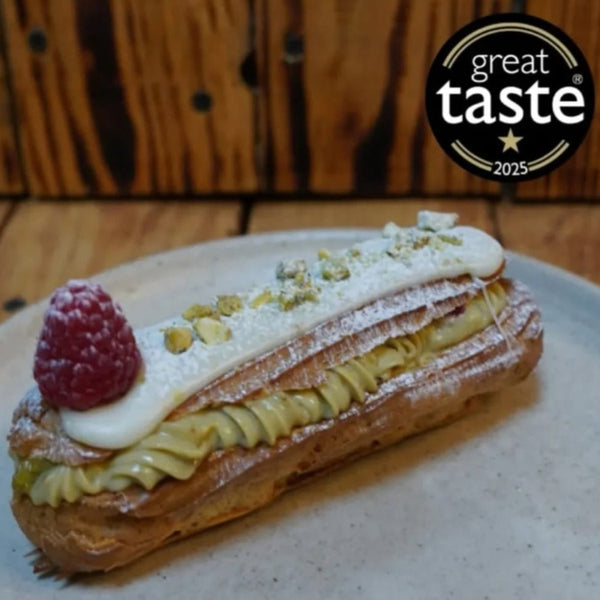 Pastry with raspberry and cream on a plate, featuring the Great Taste 2025 logo.
