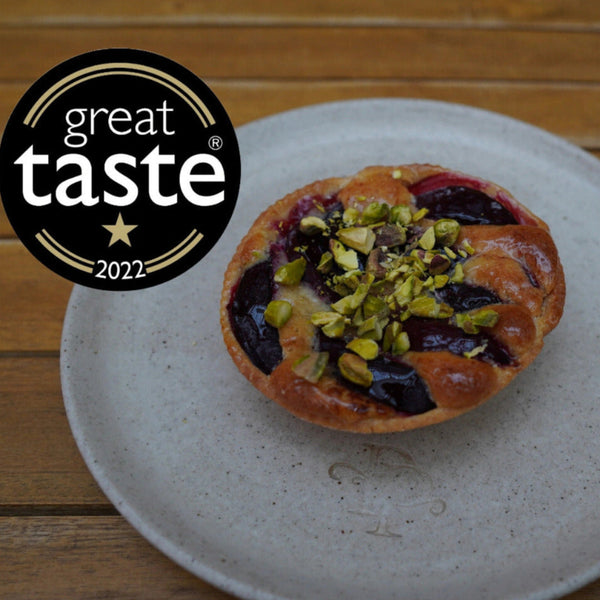 Plum and Pistachios Frangipane tart on a plate, featuring the Great Taste 2022 logo.