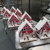Decorative gingerbread houses on a metal surface in a kitchen setting